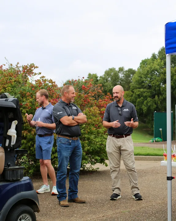 Three participants gathering beside the golf carts before the outing.