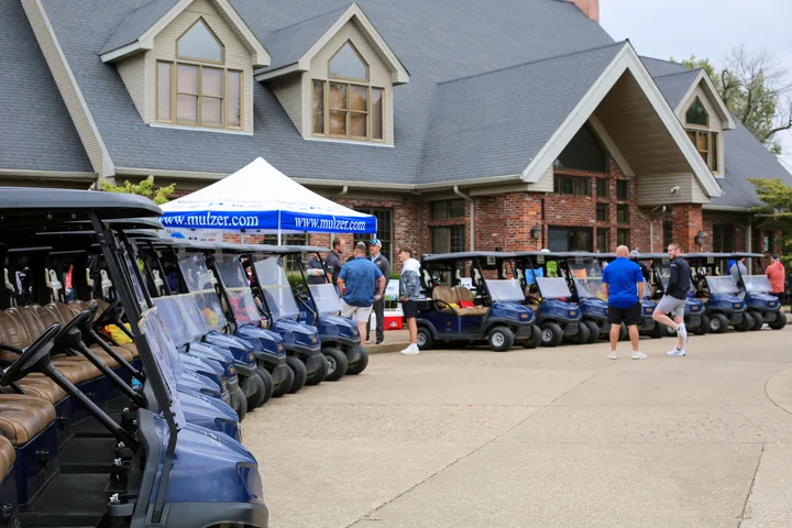Golf carts and the Mulzer registration tent outside The Pearl Club clubhouse.