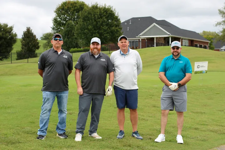 Four golfers posing with their clubs before starting the round.