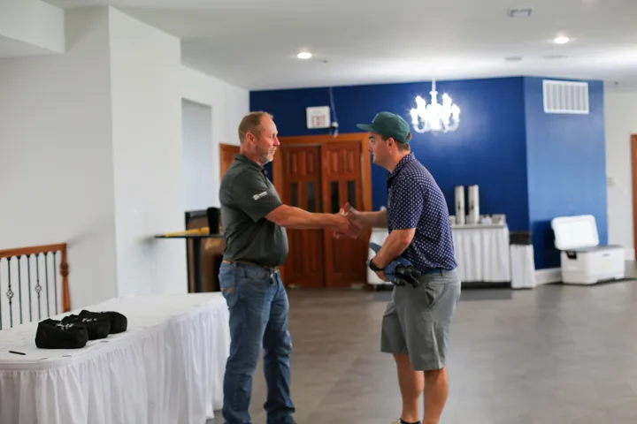 Two participants shaking hands inside The Pearl Club clubhouse.
